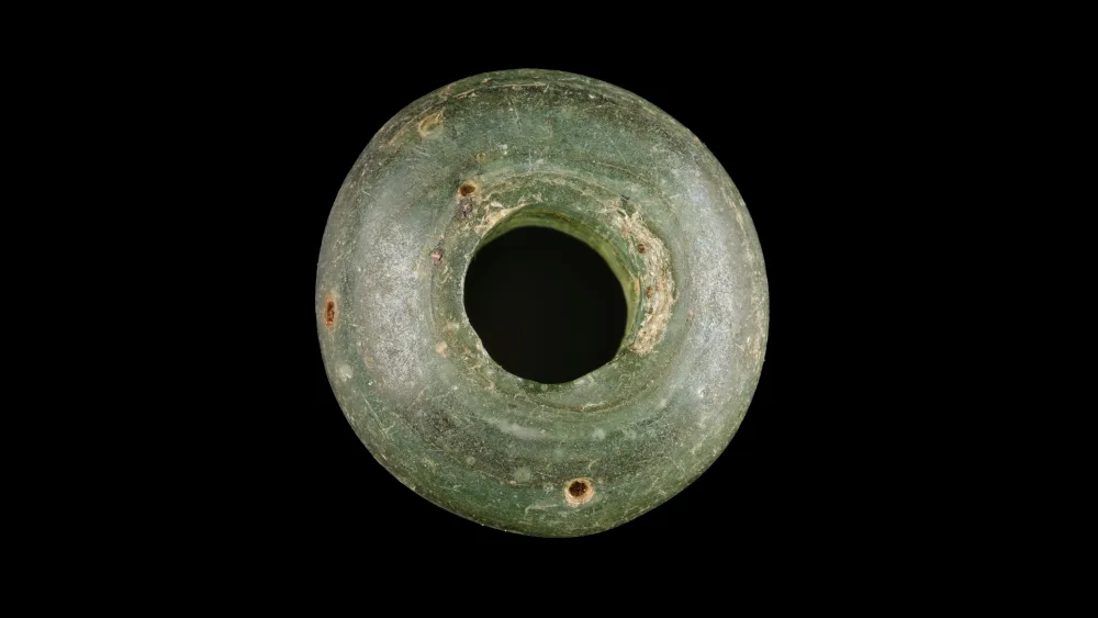 A green-coloured hoop bead, on a black background