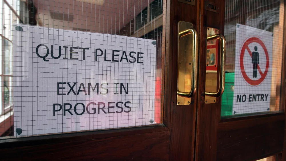 A sign saying 'quiet please, exams in progress, pinned to a set of doors