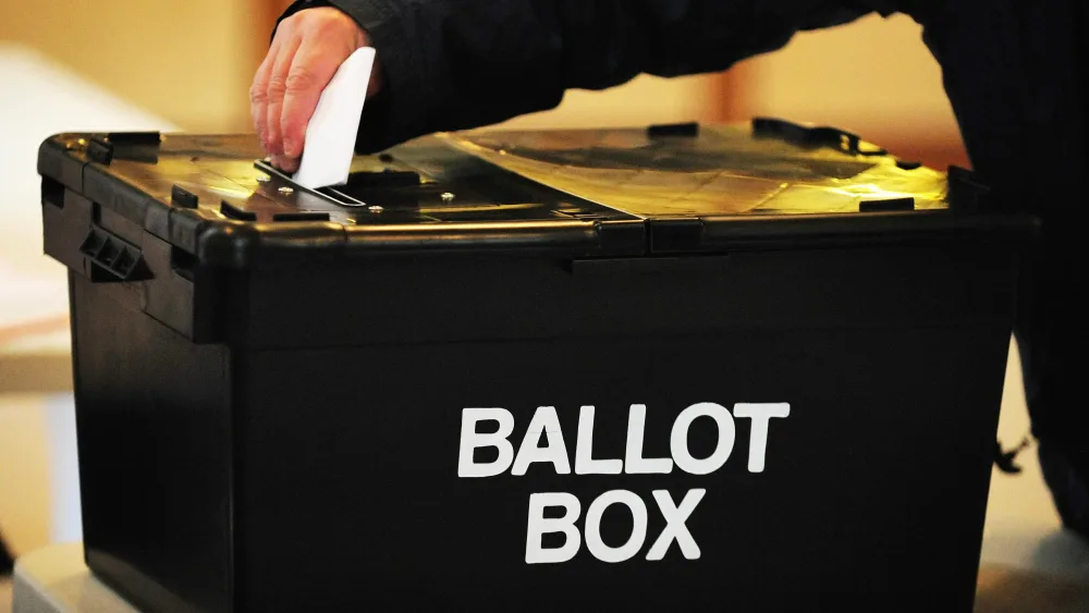 Person putting a ballot paper into a ballot box