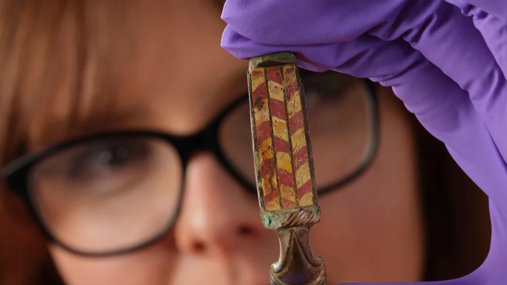 Assistant Curator Bethany Simpson with the brooch