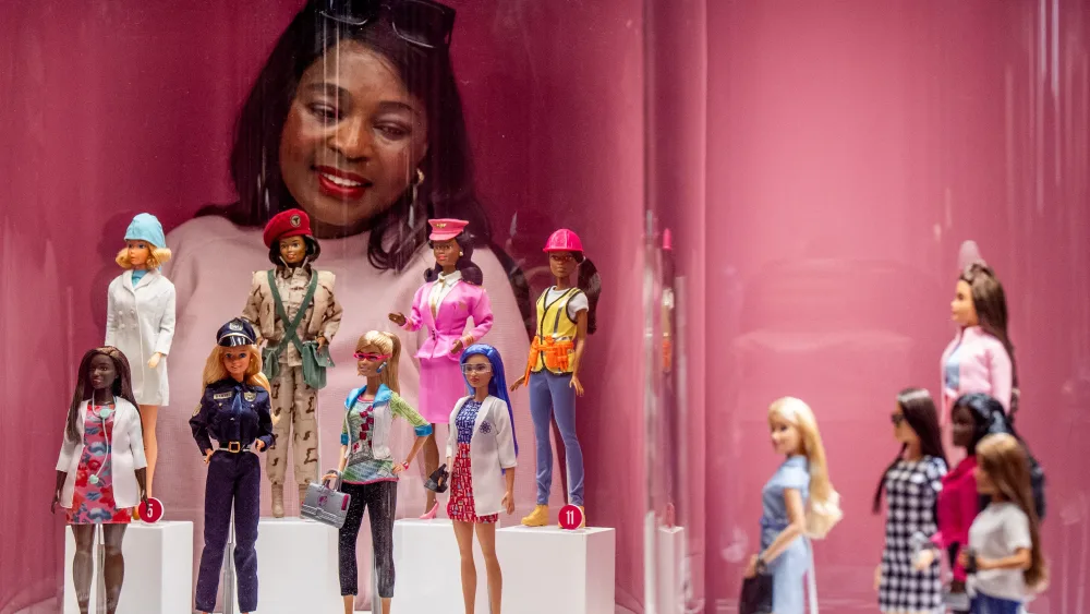 A woman looking at an exhibition of Barbie dolls