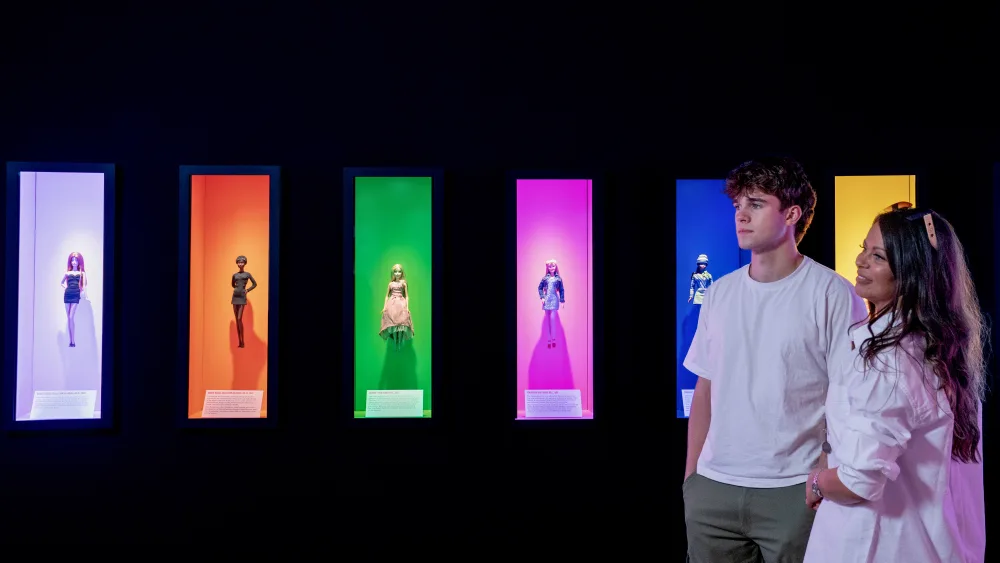 A man and woman look at a Barbie exhibition
