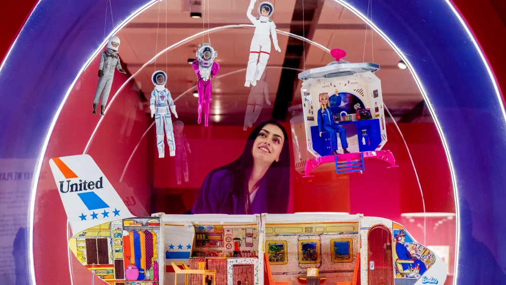 A woman looking at a Barbie exhibition
