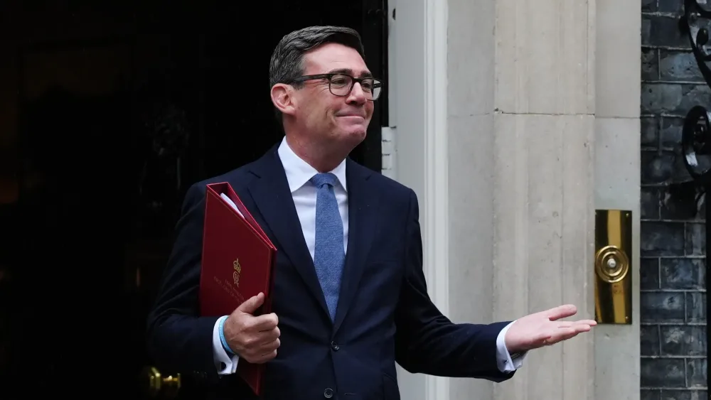 Andy Burnham standing outside No 10, holding a red folder