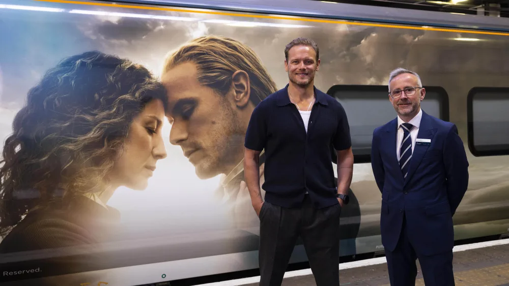 Sam Heughan with Graham Kelly in front of the Outlander-wrapped train