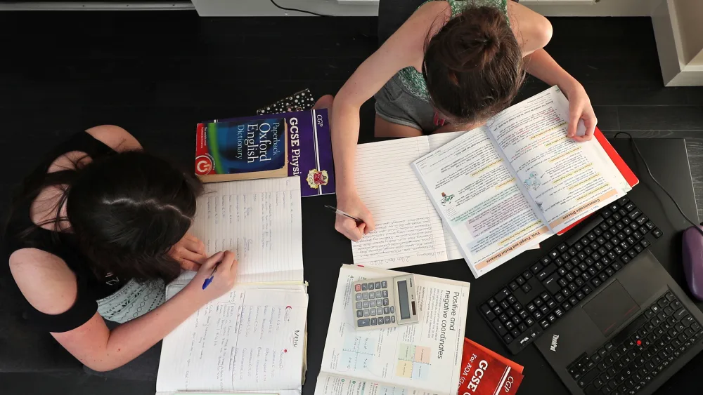 View from above of two girls doing their school work at home during the pandemic