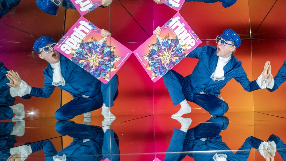 A performer with the Fringe programme reflected in mirrors
