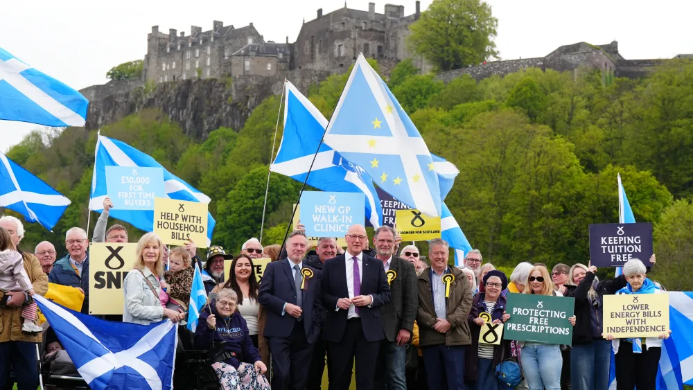 John Swinney smiling while SNP supporters, waving flags and placards, with Stirling Castle above them