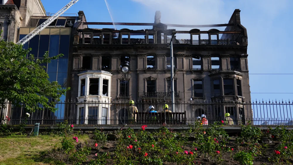 View of a fire-damaged and blackened building, under a blue sky