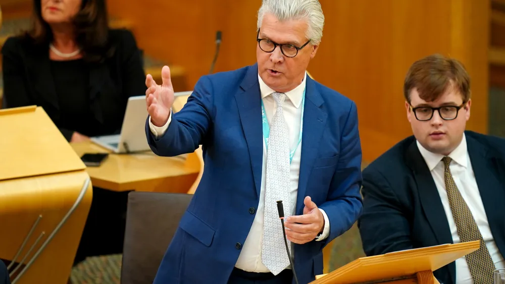 Malcolm Offord with one arm raised while speaking in Holyrood
