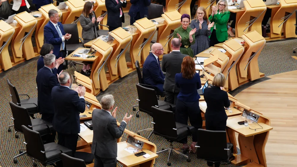 SNP MSPs standing in Holyrood and clapping