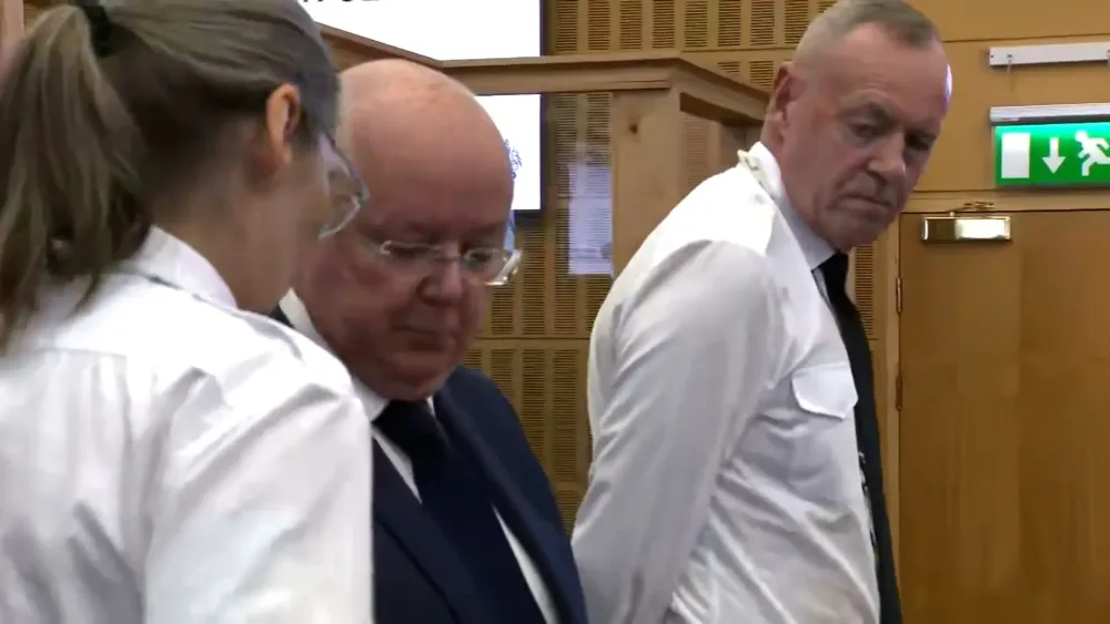 Peter Murrell flanked by security officers in court