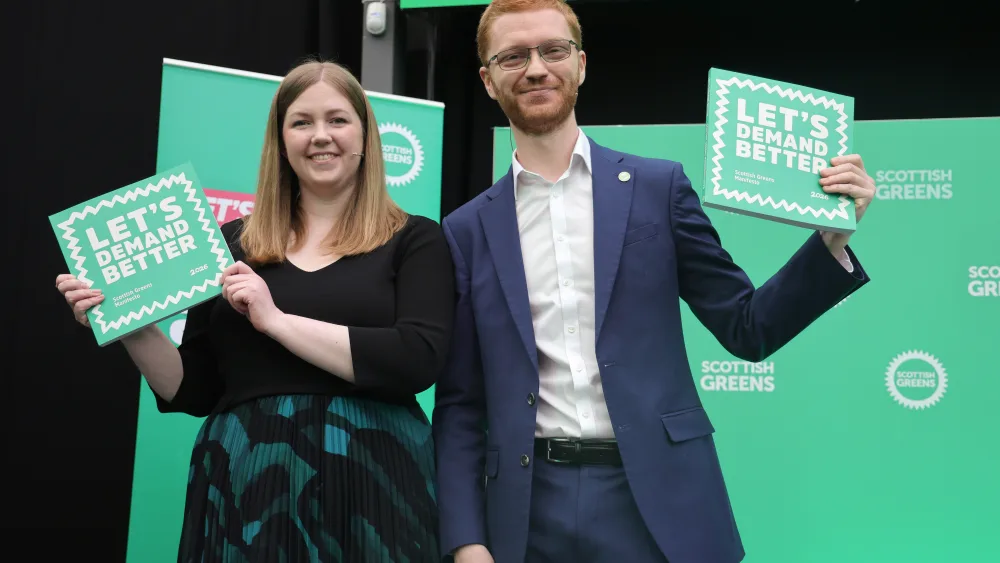 Gillian Mackay and Ross Greer smiling while holding up Scottish Green signage