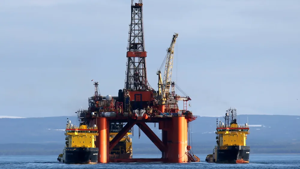 An oil rig with two tugs alongside it