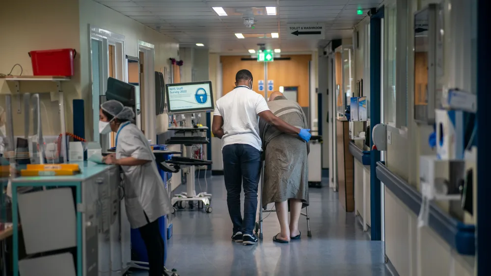 A nurse helping an elderly patient on a hospital ward