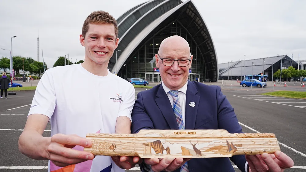 Duncan Scott and John Swinney smiling while holding up the King's Baton