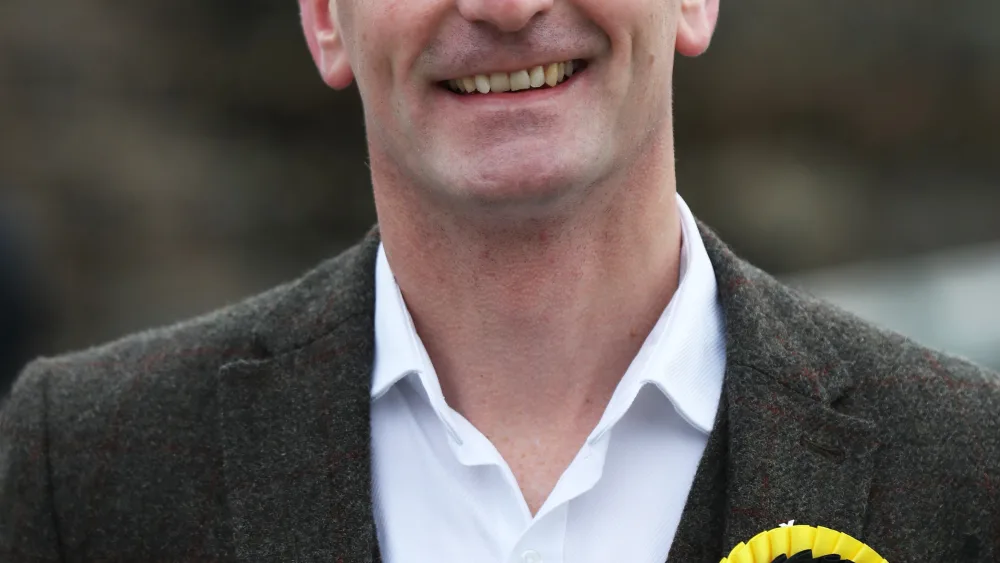 Dave Doogan smiling, wearing an SNP rosette