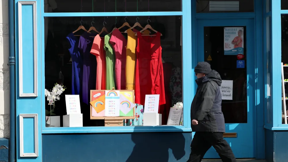 A shopper walking past the window of a charity shop