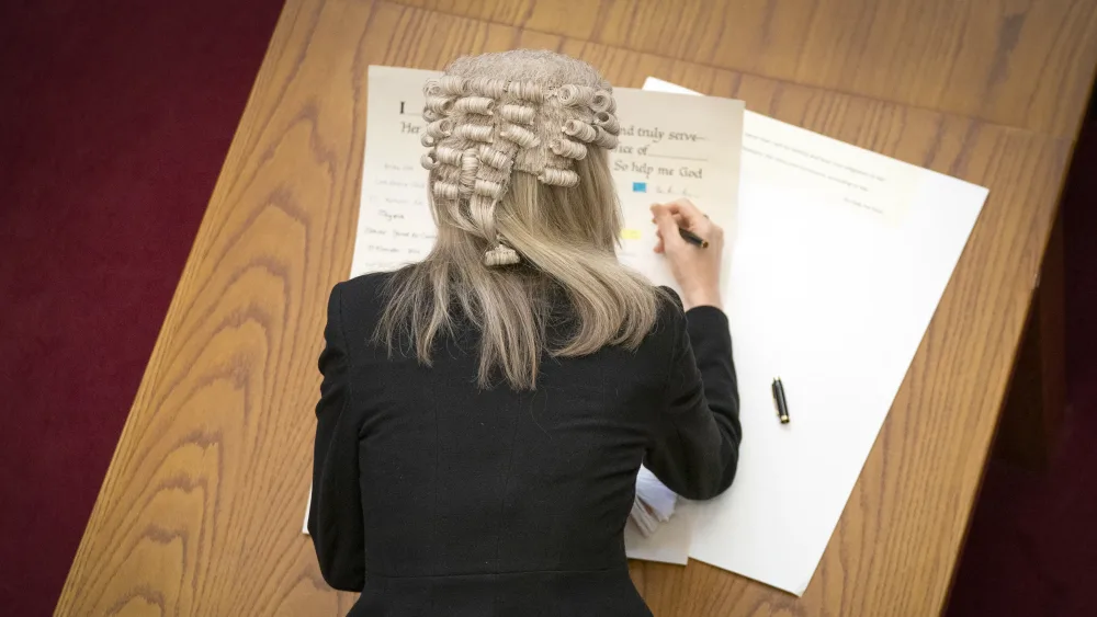 A lawyer in wig writing in a paper