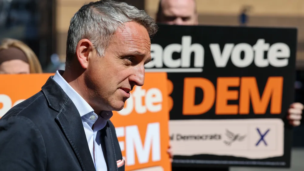 Alex Cole-Hamilton looking serious in front of some Lib Dem placards