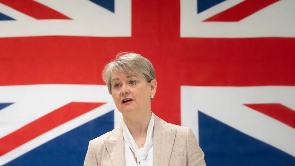 Yvette Cooper speaking, with a large British flag behind her