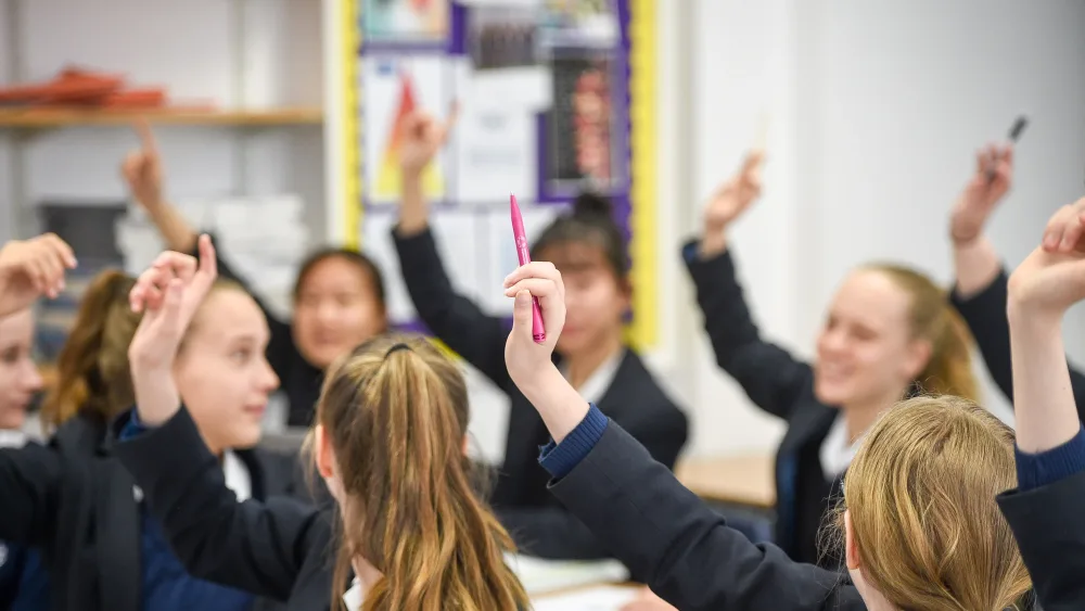 High school pupils raising their hands to ask a question