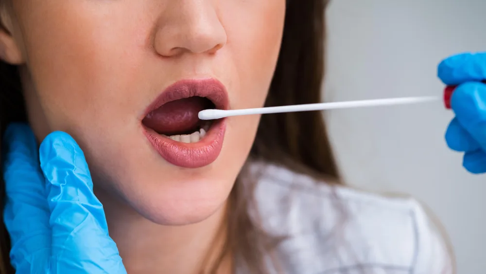 Close-up of a saliva sample being taken from a woman's mouth