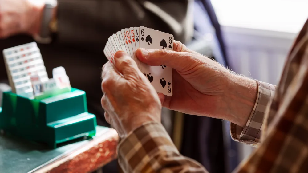 Older woman's hands holding a suite of cards.