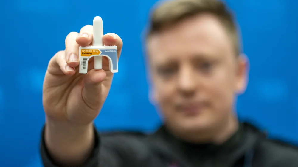 A man holding up a device for the spraying of naloxone