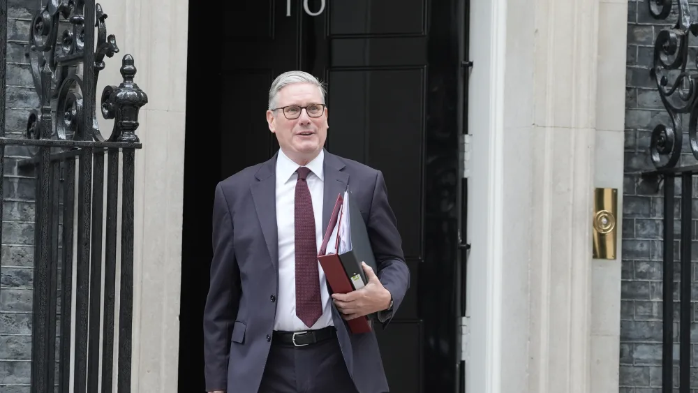 Sir Keir Starmer smiling while exiting Number 10, carrying two folders