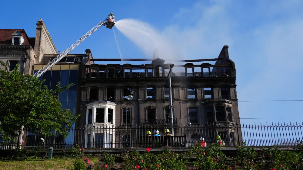 Firefighters spray water from a high platform on to a building which shows signs of extensive fire damage