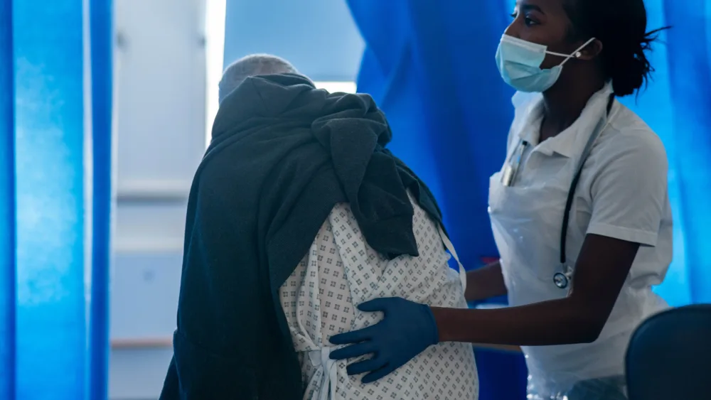 A nurse helping an elderly patient on a hospital ward