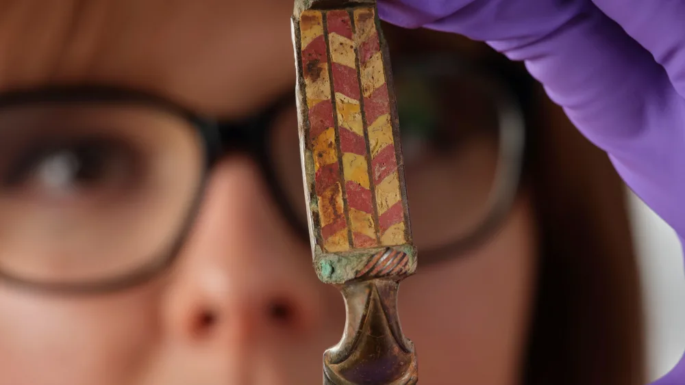 Assistant curator Bethany Simpson holding a Roman brooch