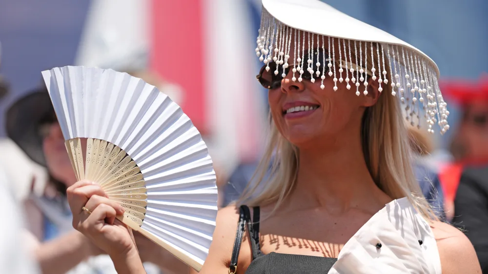 A racegoer fans herself in the hot weather on day four of Royal Ascot at Ascot Racecourse, Berkshire