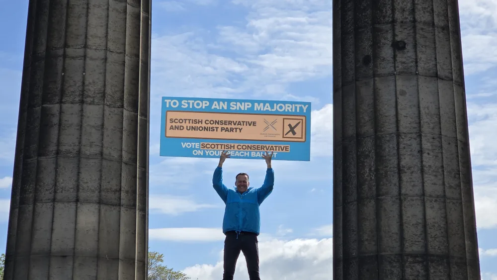 Russell Findlay holds a 'vote Tory' sign at the top of Calton Hill