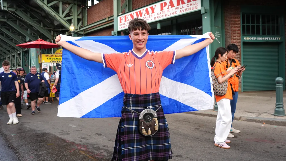 A Scotland fan smiling while holding up a flag