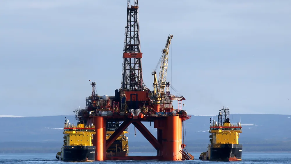 An oil rig at sea, flanked by ships