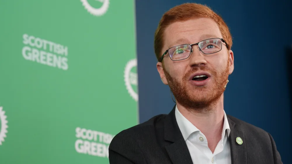 Ross Greer speaking, in front of Scottish Green signage