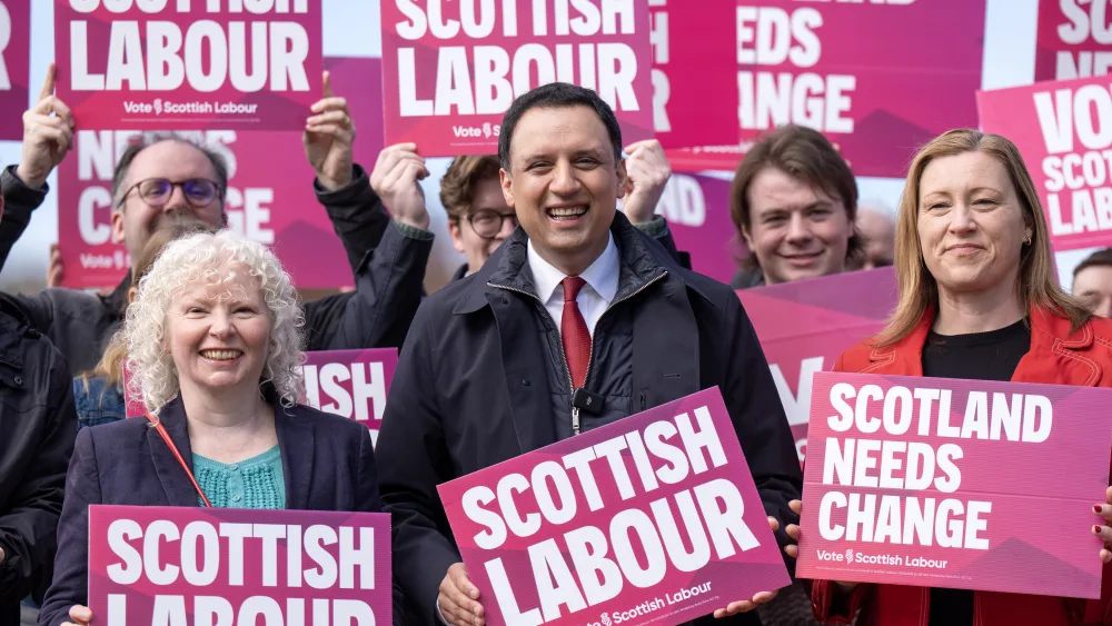 Anas Sarwar smiling amongst a group of Labour supporters holding placards reading 'Scottish Labour' and 'Scotland needs change'
