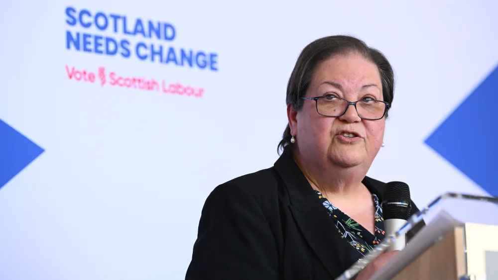 Dame Jackie Baillie speaking from a lectern, in front of Scottish Labour signage