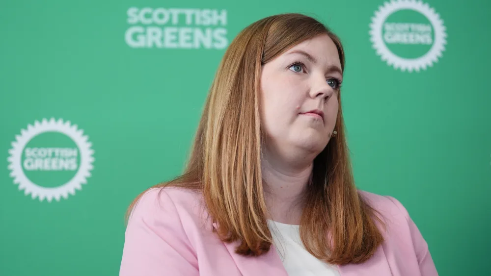 Gillian Mackay standing in front of Scottish Green signage