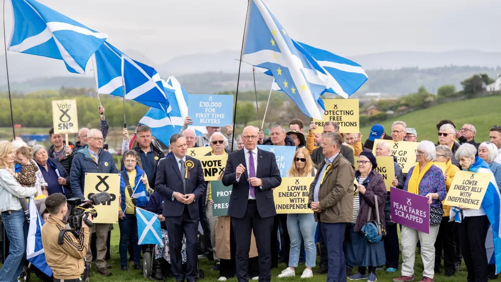 John Swinney smiling in a large group of SNP supporters outside