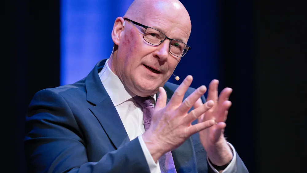 John Swinney gestures while on stage