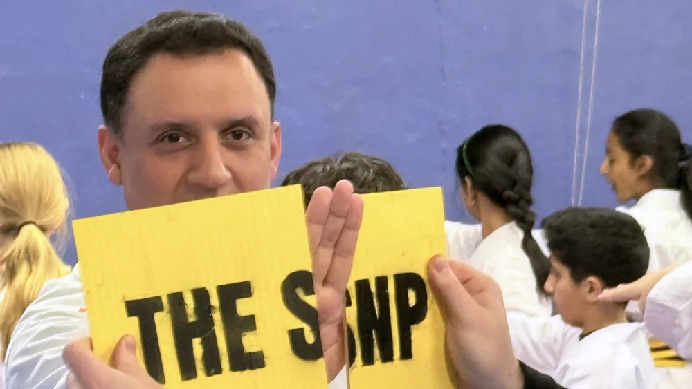 Scottish Labour leader Anas Sarwar uses his hand to snap an SNP sign
