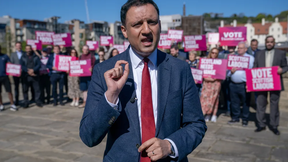 Anas Sarwar speaking in front of a large group of Scottish Labour supporters, holding placards