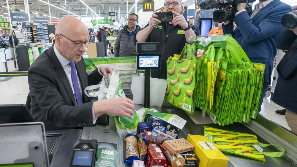 John Swinney working at a supermarket till packing shopping