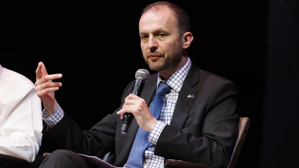 Stephen Gethins speaking into a microphone he is holding, while seated