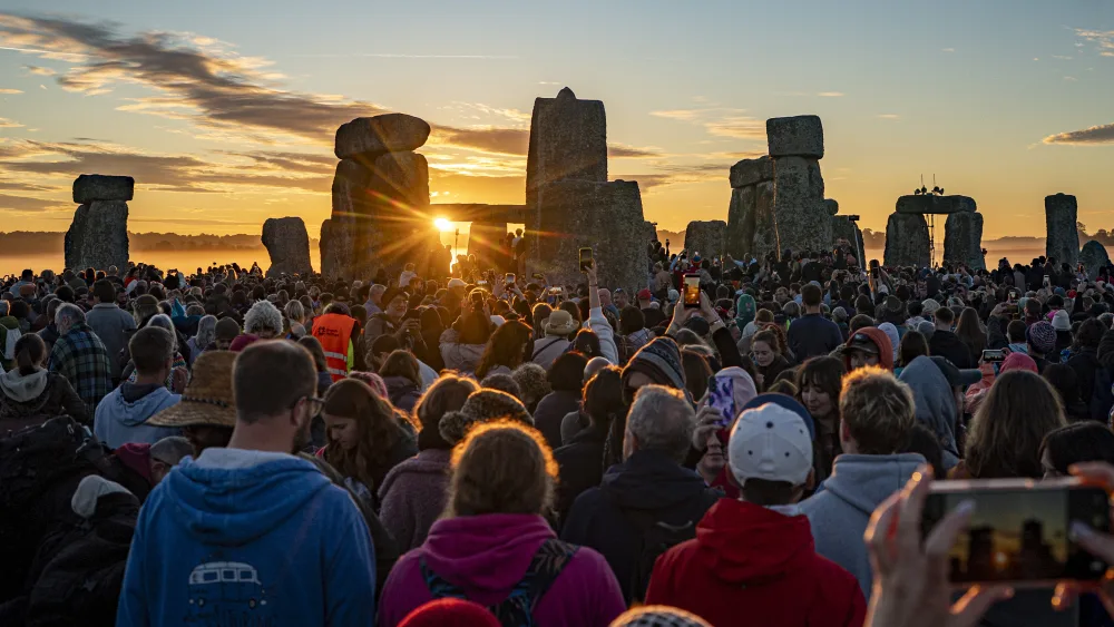 The sun rises through the stones as people gather at Stonehenge, Wiltshire,