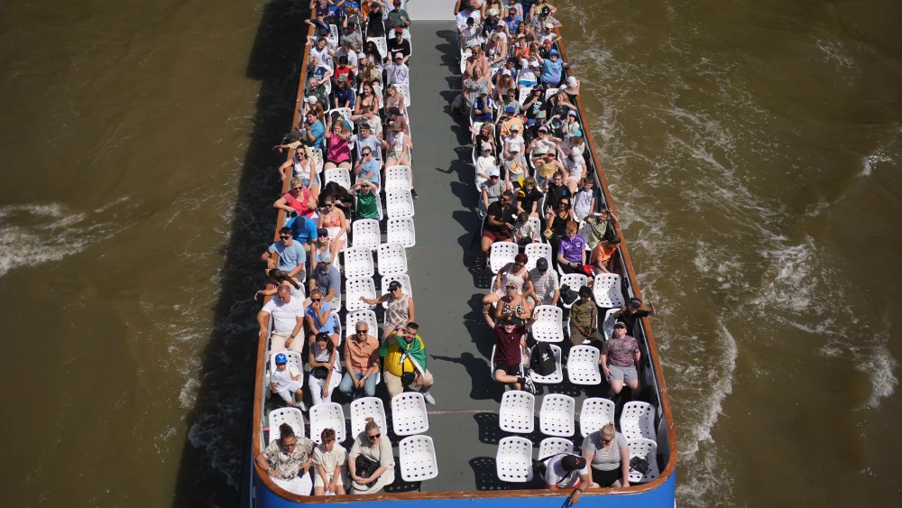 People sitting in the sun on the top of a river boat