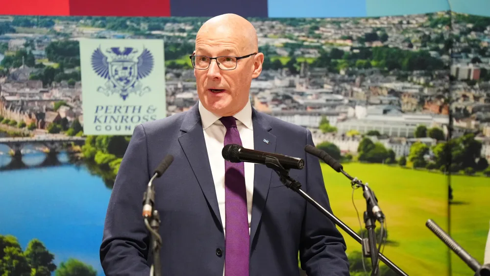 John Swinney making a speech in front of some microphones
